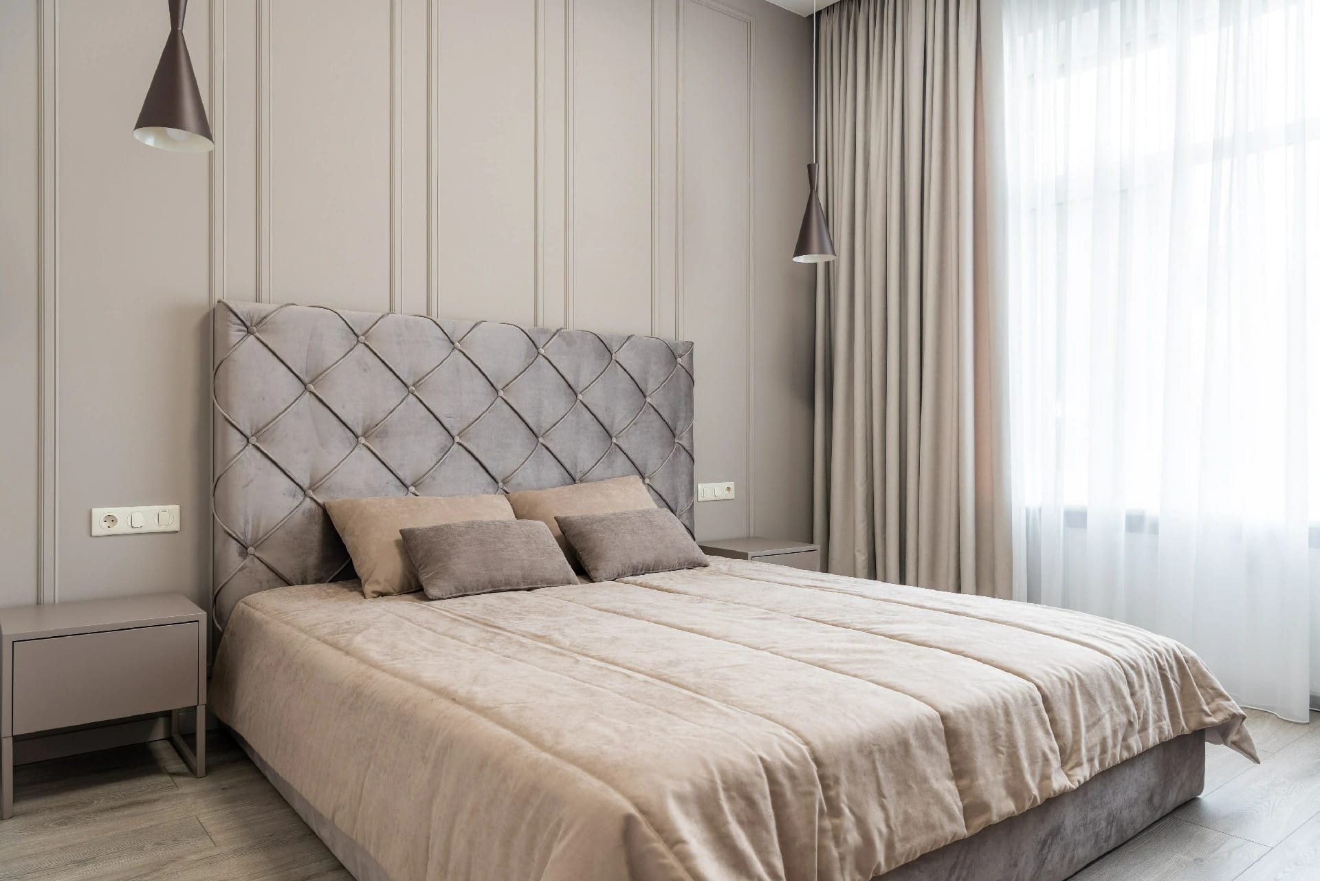 Quarto com cortinas claras, cabeceira capitonê e boiserie