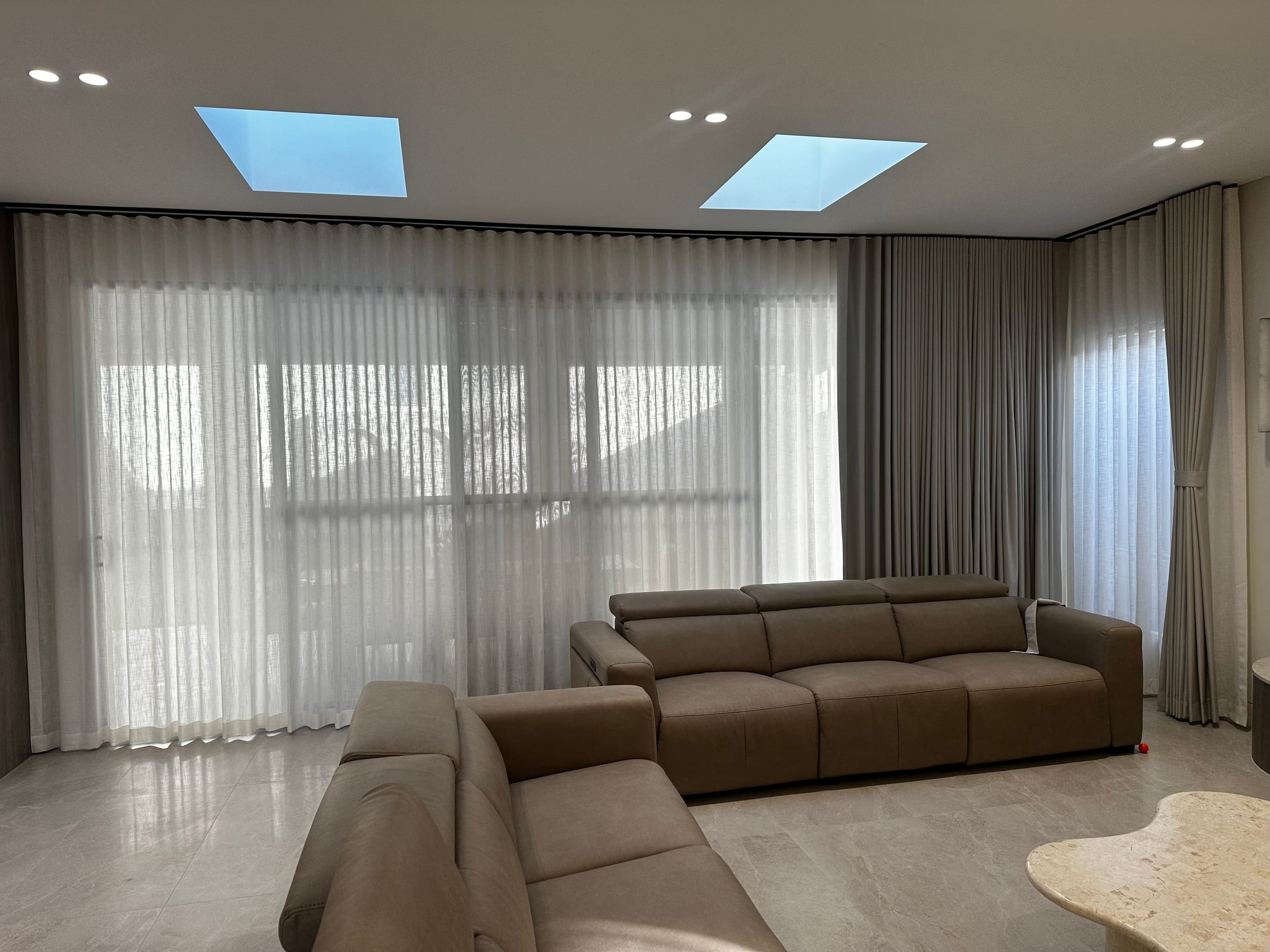 Sala com pé-direito alto, cortinas wave e luz natural difusa